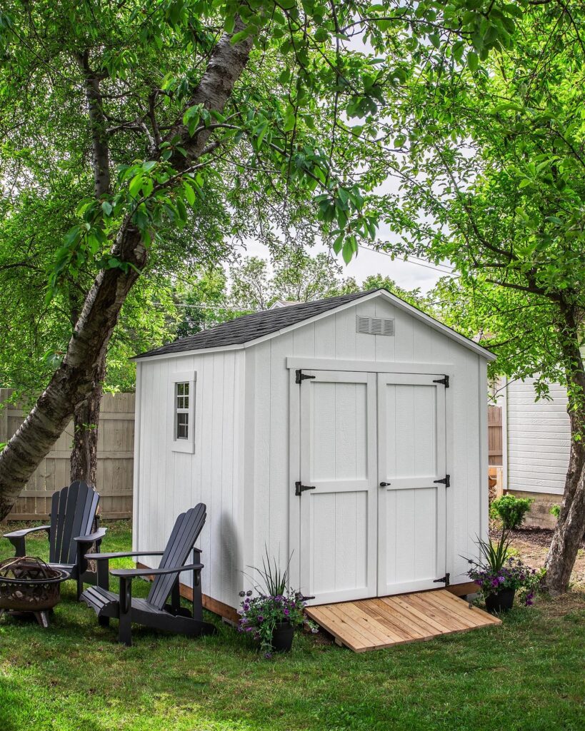 Custom white storage shed in Utah with double doors, designer paint colors, and a handcrafted wooden ramp built by Solitude Custom Sheds.