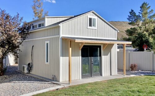 15x21 backyard standalone golf simulator studio in Herriman, Utah built by Solitude Custom Sheds featuring modern gray exterior with white trim, and frosted glass dormer windows. Perfect for home golf simulator studios, backyard offices, or backyard gyms.