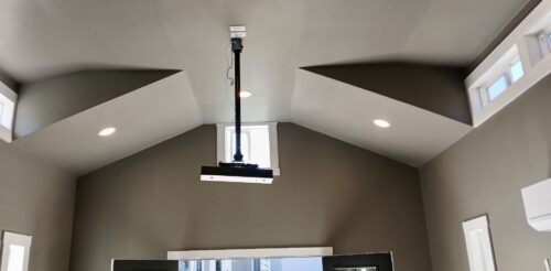 Interior of custom golf simulator studio built by Solitude Custom Sheds in Herriman, Utah, featuring modern wall finishes, mini split HVAC system, and natural light from transom and vertical windows. Ideal for year-round home golf practice or a stylish backyard office.