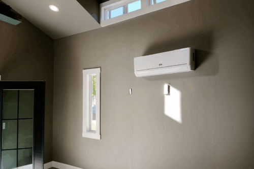 Interior of custom golf simulator studio built by Solitude Custom Sheds in Herriman, Utah, featuring modern wall finishes, mini split HVAC system, and natural light from transom and vertical windows. Ideal for year-round home golf practice or a stylish backyard office.