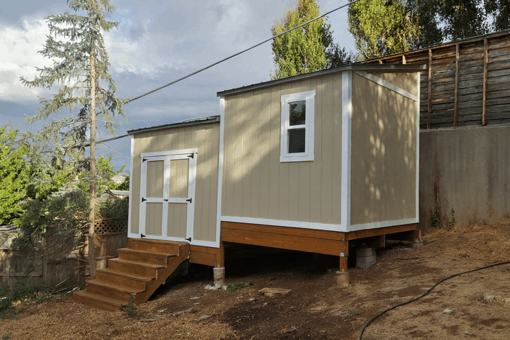 Split-level 10x18 custom outdoor storage shed in Salt Lake City, Utah with elevated foundation, double doors, and beige siding by Solitude Custom Sheds
